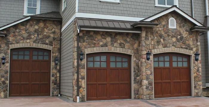 Dark wood carriage-house garage doors on a stone-front home